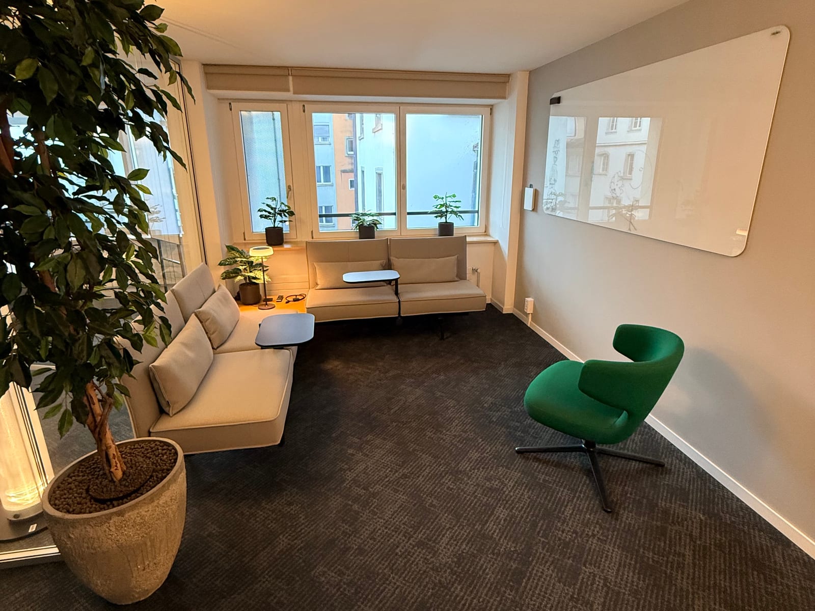 The ship26 lounge — low sofas, a green armchair and a whiteboard, lit by a row of windows