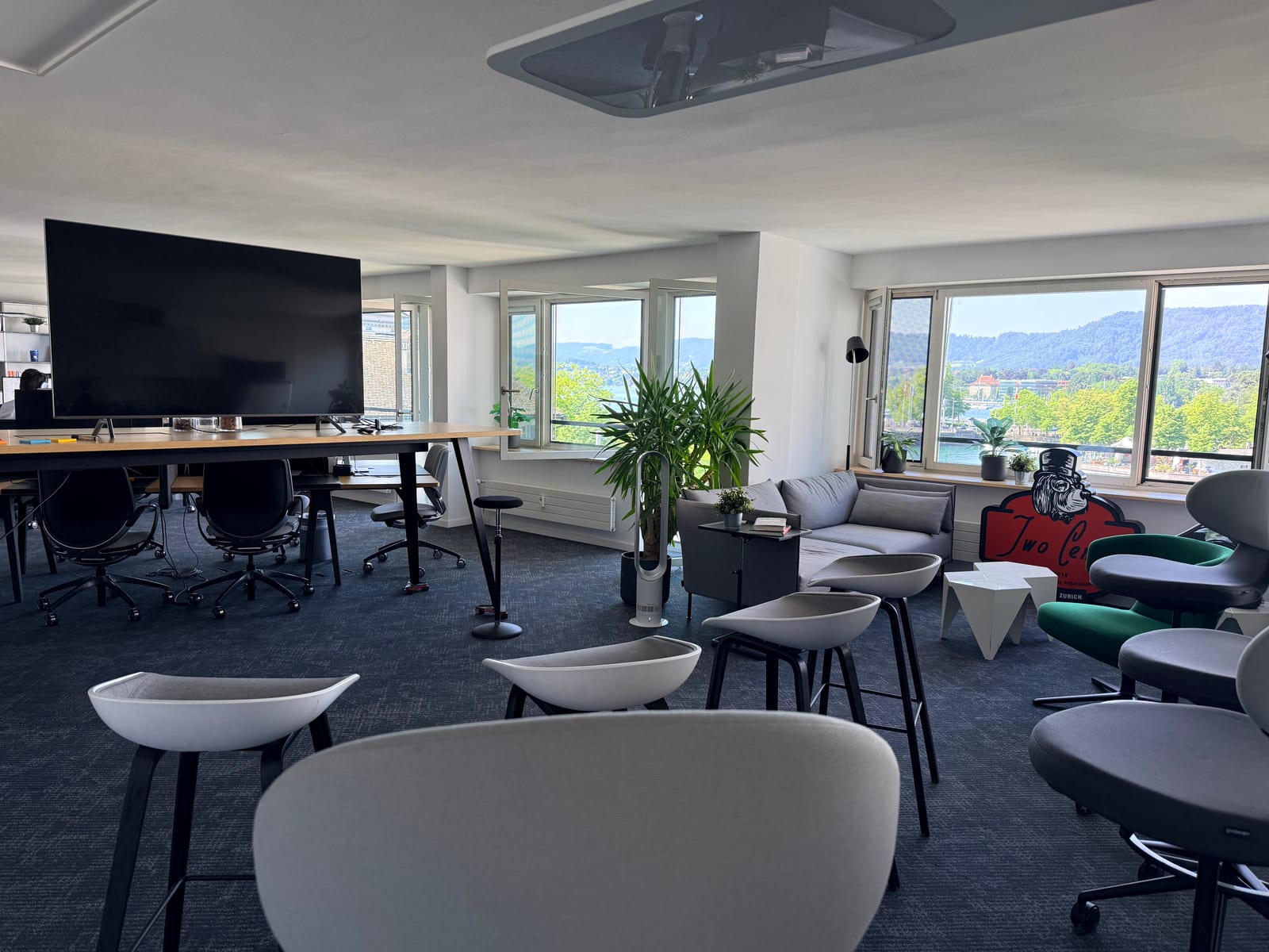 The ship26 event space set up with stools and armchairs facing a screen, the lake visible through the windows